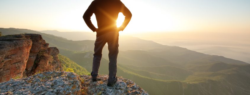 Man on top of mountain watching the sun