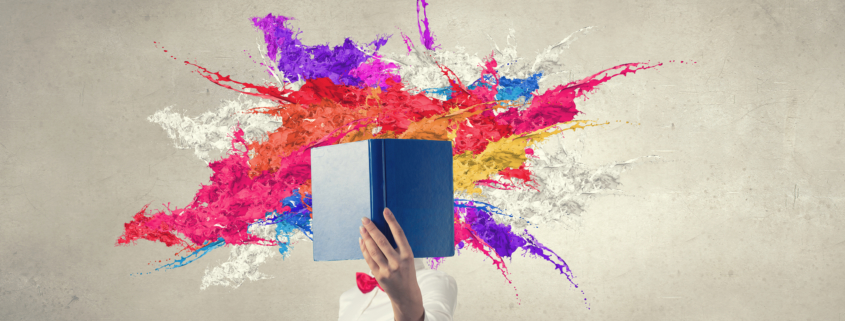 Woman with opened book against her face and colorful splashes flying out