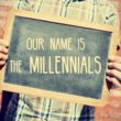 Person holding up a chalkboard saying 'Our name is the Millenials'
