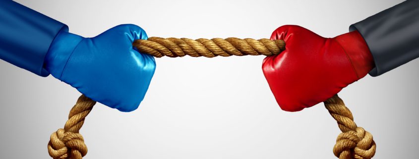Blue boxing glove and a red boxing glove each holding one end of a rope and playing tug of war