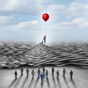 Man floating upwards holding a balloon in one hand while he's pulling a maze with the other while his colleagues follow him