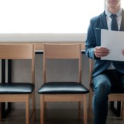 Person in business attire sitting next to two empty chairs holding their resume
