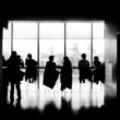 Silhouette of people sitting around a table in a conference room overlooking a city