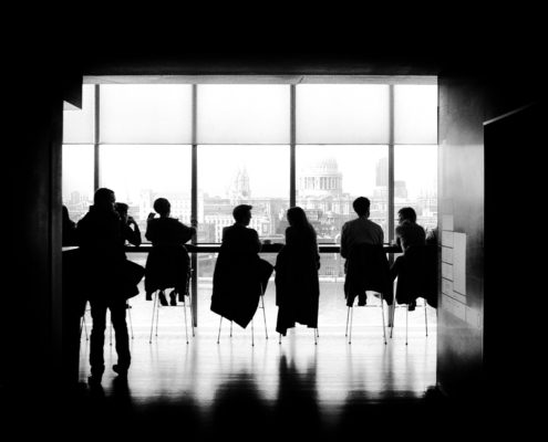 Silhouette of people sitting around a table in a conference room overlooking a city