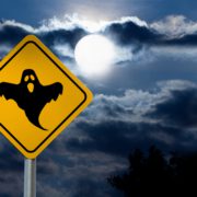 Dark Cloudy Sky with Full Moon and the road Sign (Yellow Square) is a black Silhouette of the Halloween Ghost