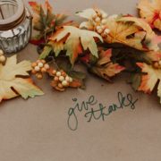 Autumn leaves decorated over brown butcher paper with 'give thanks' written on it